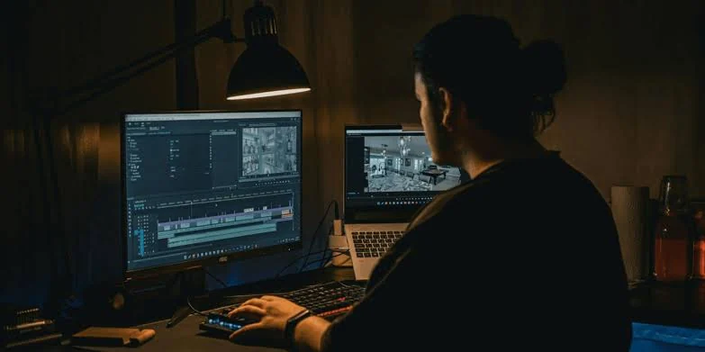 Người dựng video AI làm việc trước nhiều màn hình biên tập trong phòng tối